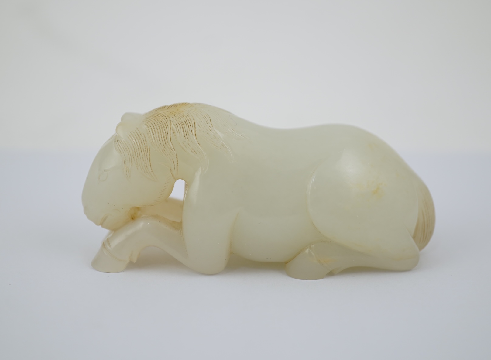 A Chinese white jade figure of a recumbent horse